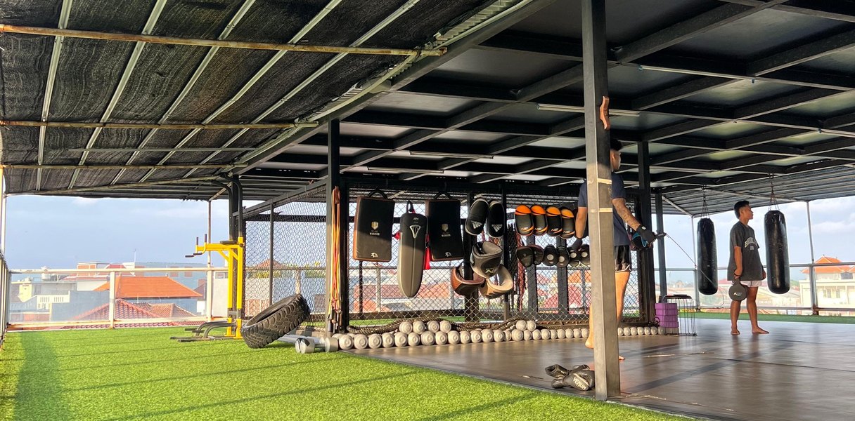 Open-air rooftop training deck at Teuku Umar with heavy bags, turf and tyres
