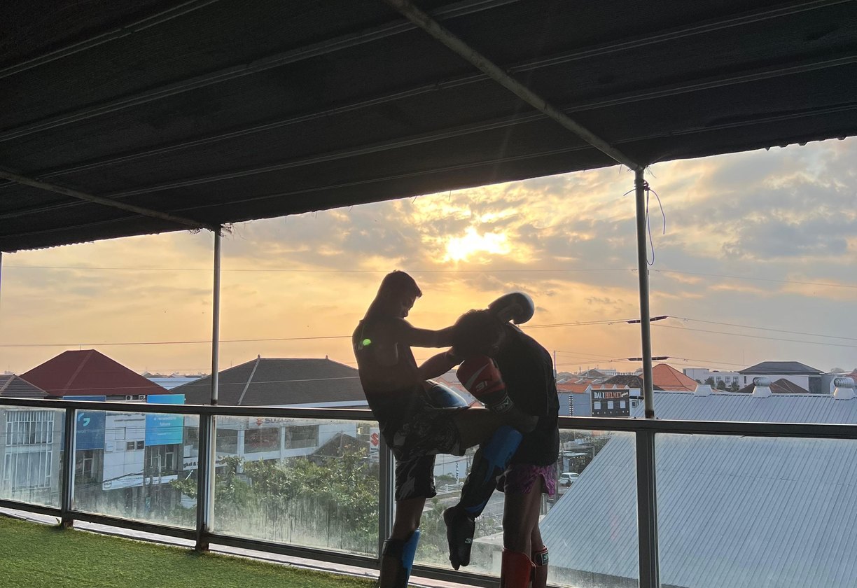 Two fighters drilling clinch work against a sunset sky on the open-air rooftop deck